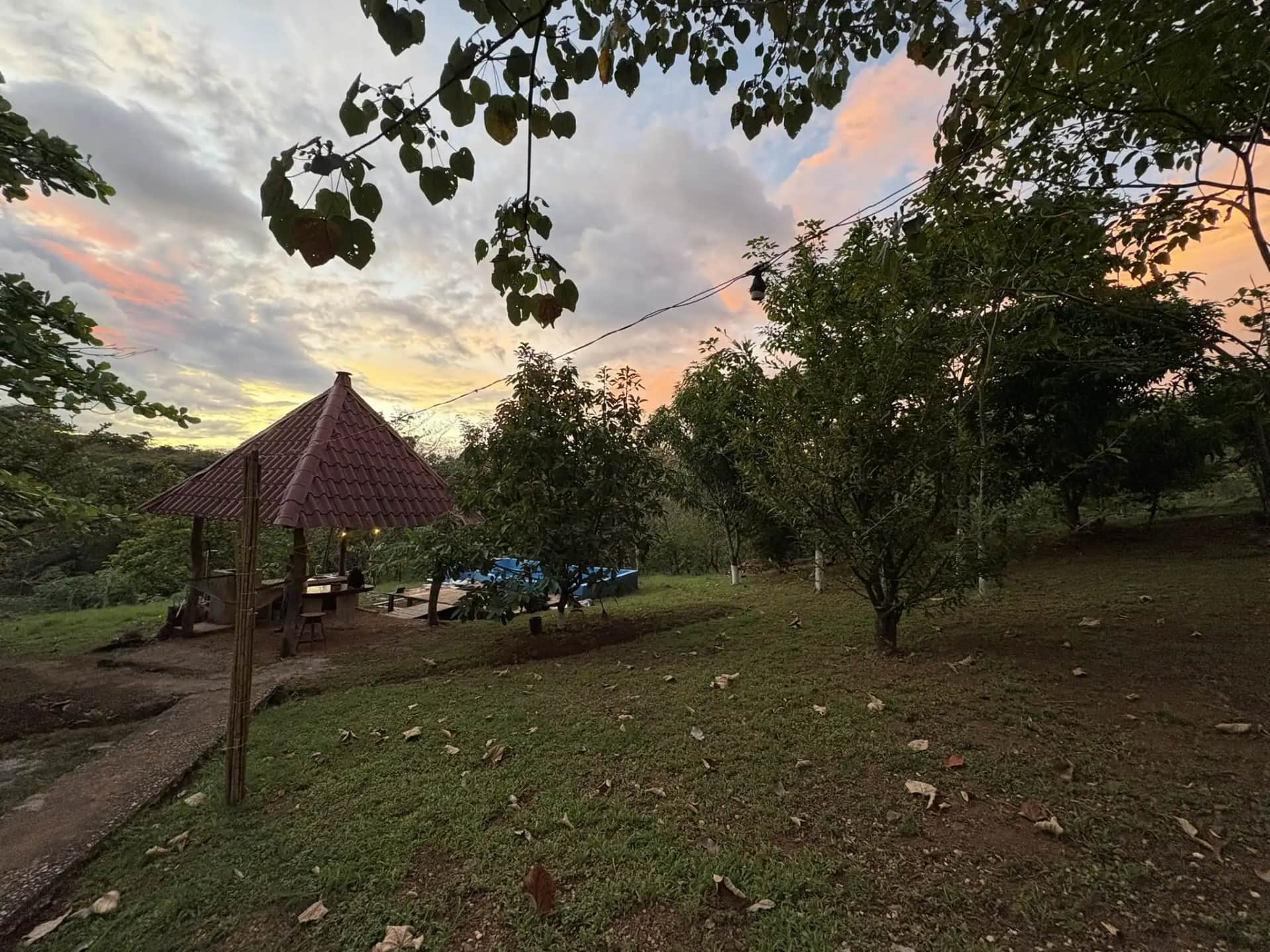 Jardín y rancho de Pura Noche al atardecer, rodeados de árboles